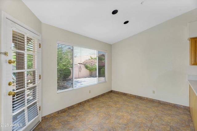 spare room with baseboards and stone finish floors