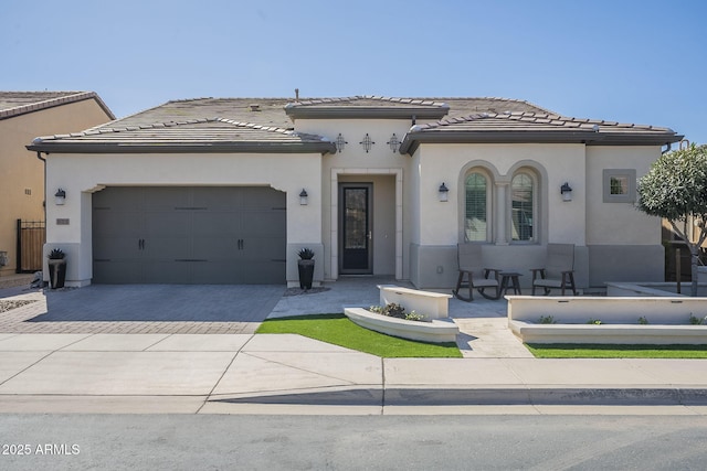 view of front of property featuring stucco siding, an attached garage, driveway, and a tiled roof