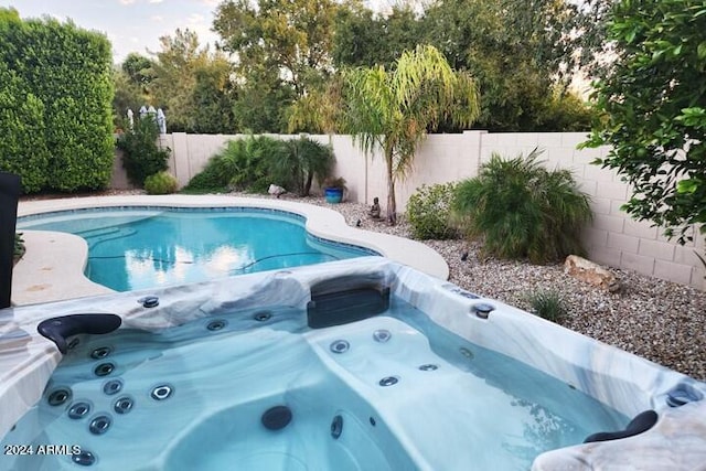 view of swimming pool featuring a hot tub