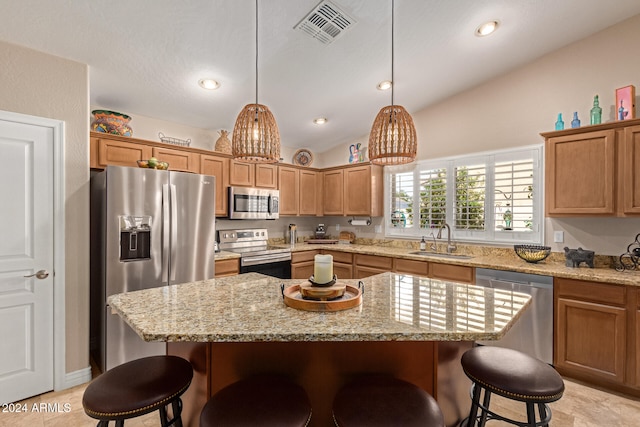 kitchen with lofted ceiling, appliances with stainless steel finishes, sink, and a center island