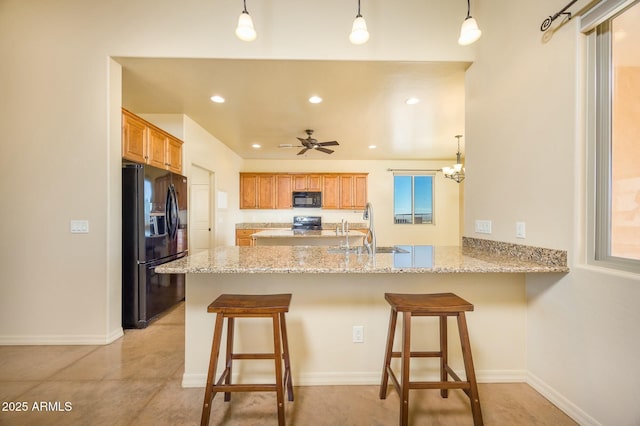 kitchen with hanging light fixtures, sink, kitchen peninsula, and black appliances