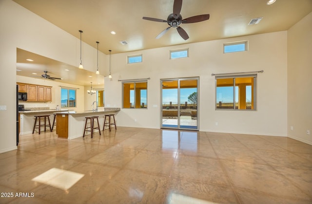 unfurnished room featuring a towering ceiling, sink, and ceiling fan