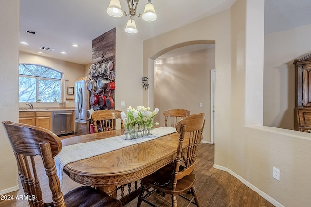 dining space with sink, dark hardwood / wood-style floors, and an inviting chandelier