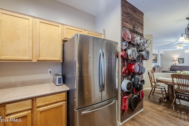 kitchen featuring ceiling fan, hanging light fixtures, stainless steel fridge, light hardwood / wood-style floors, and light brown cabinetry