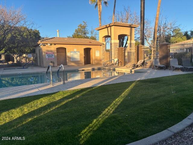 rear view of house featuring a lawn, a patio area, and a community pool