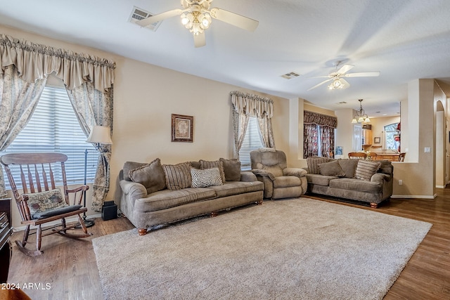 living room featuring a wealth of natural light, ceiling fan with notable chandelier, and hardwood / wood-style flooring