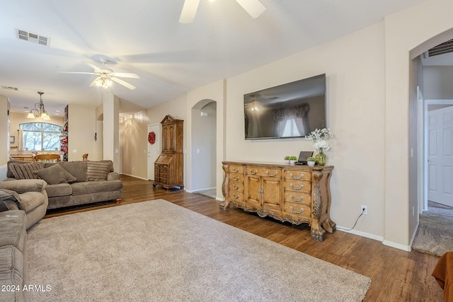 living room featuring ceiling fan with notable chandelier and dark hardwood / wood-style floors