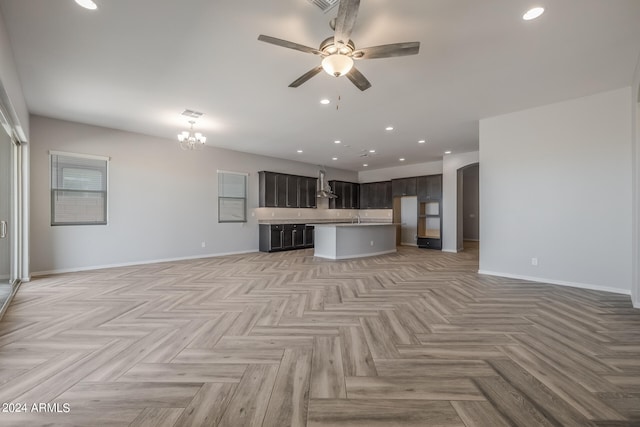 unfurnished living room featuring light parquet floors and ceiling fan with notable chandelier