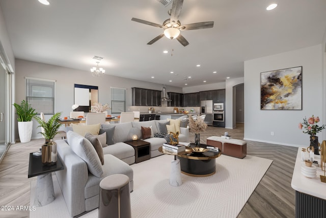 living room featuring ceiling fan with notable chandelier and light parquet flooring