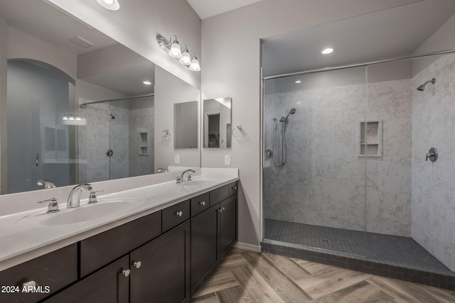 bathroom featuring a tile shower, parquet floors, and dual bowl vanity