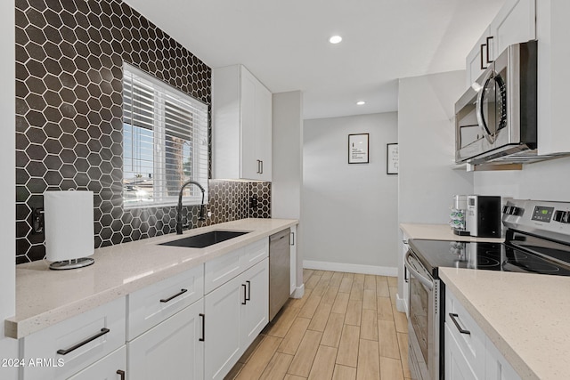 kitchen with white cabinetry, sink, light stone countertops, and appliances with stainless steel finishes