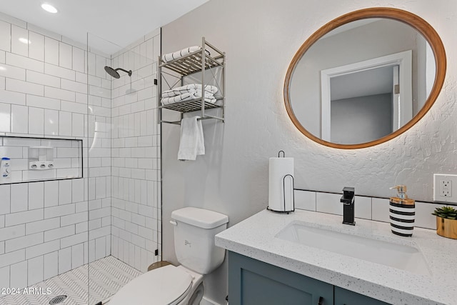 bathroom featuring tiled shower, vanity, and toilet