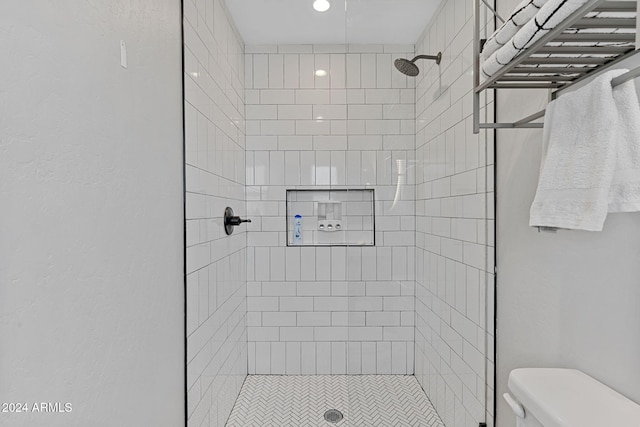 bathroom featuring tiled shower and toilet