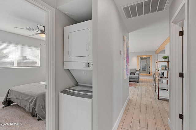 laundry room featuring stacked washer / drying machine and light wood-type flooring