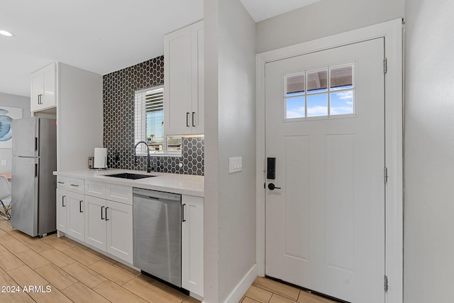 kitchen with appliances with stainless steel finishes, white cabinetry, and plenty of natural light