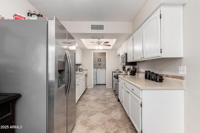 kitchen with a textured ceiling, stainless steel appliances, ceiling fan, separate washer and dryer, and white cabinetry