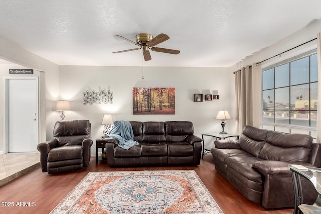 living room with ceiling fan, dark hardwood / wood-style flooring, and a textured ceiling