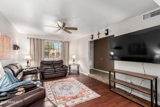 living room with ceiling fan, dark hardwood / wood-style flooring, and a textured ceiling