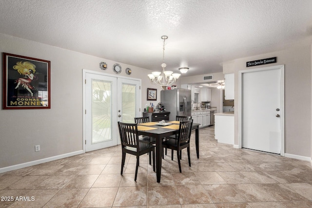 dining space with a textured ceiling, an inviting chandelier, sink, and french doors