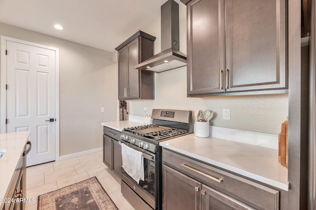 kitchen with wall chimney exhaust hood, gas range, dark brown cabinets, and light tile patterned floors