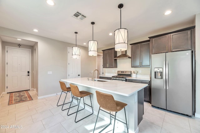 kitchen featuring appliances with stainless steel finishes, pendant lighting, dark brown cabinetry, a kitchen island with sink, and sink