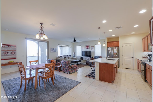 tiled dining area featuring sink and ceiling fan with notable chandelier