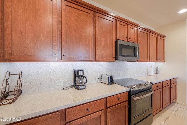 kitchen with decorative backsplash, light stone countertops, and appliances with stainless steel finishes