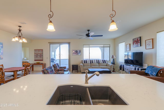 kitchen featuring sink, pendant lighting, light stone counters, and ceiling fan