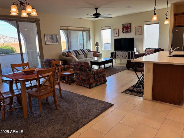 dining space with sink, ceiling fan with notable chandelier, and light tile patterned flooring