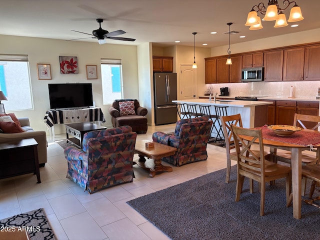 living room with sink, ceiling fan with notable chandelier, and light tile patterned floors