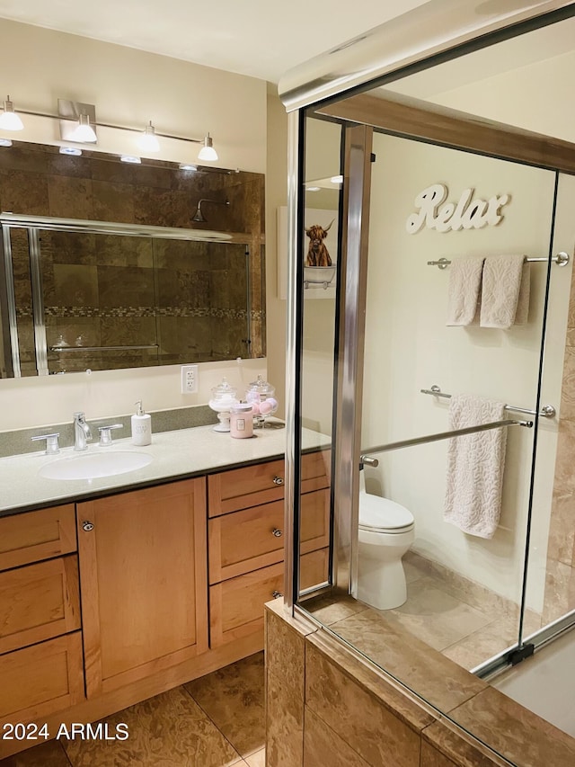 bathroom with toilet, tile patterned flooring, a shower stall, and vanity