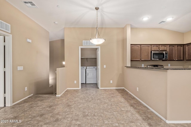 2725 E Mine Creek Rd Unit 2146, Phoenix, AZ 85024 - kitchen with stainless steel microwave, washing machine and dryer, hanging light fixtures, dark brown cabinets, and dark stone countertops