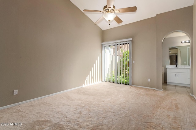 unfurnished bedroom with access to exterior, baseboards, light colored carpet, ensuite bathroom, and arched walkways