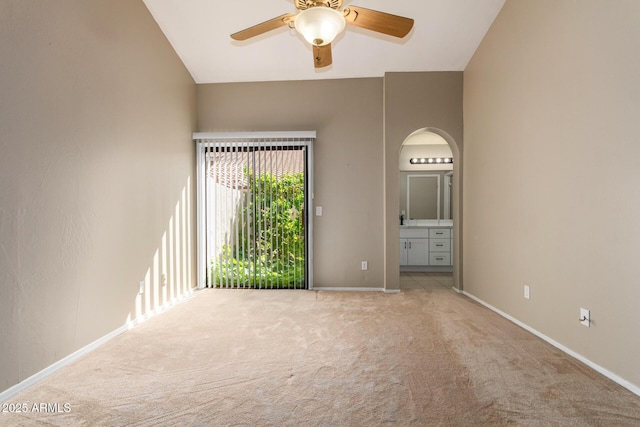 unfurnished room featuring arched walkways, light colored carpet, baseboards, and ceiling fan