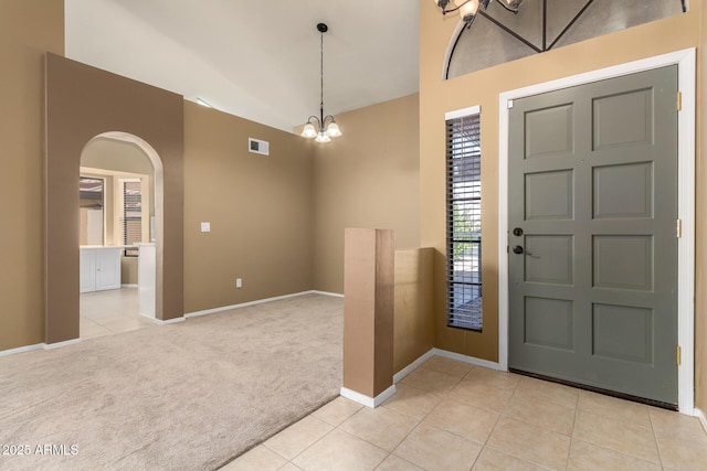 entrance foyer with visible vents, a notable chandelier, arched walkways, light tile patterned floors, and light colored carpet