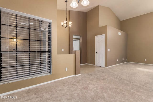 spare room with baseboards, high vaulted ceiling, an inviting chandelier, and carpet flooring