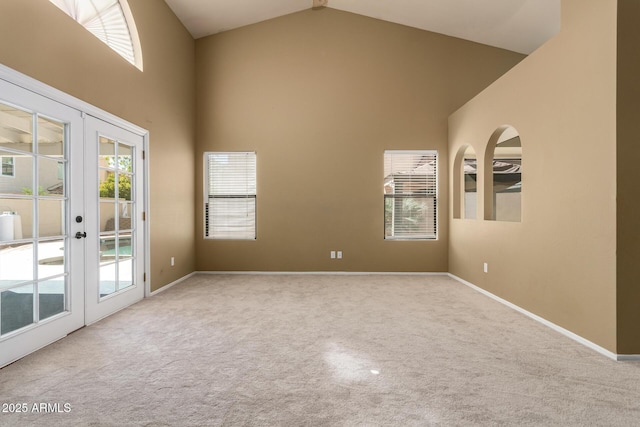 empty room with plenty of natural light, carpet, french doors, and high vaulted ceiling