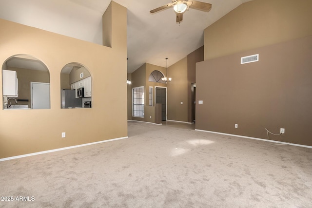 unfurnished living room featuring visible vents, baseboards, high vaulted ceiling, carpet flooring, and ceiling fan with notable chandelier