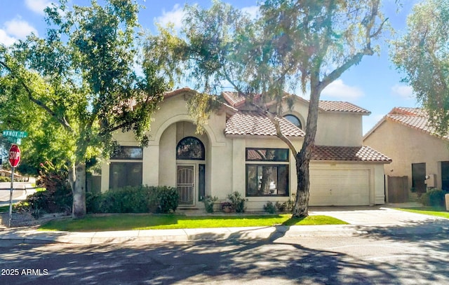 mediterranean / spanish-style home with a garage, driveway, stucco siding, and a tiled roof