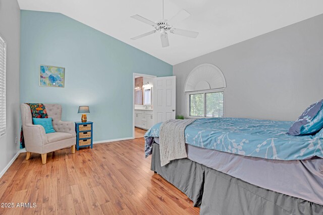 bedroom featuring lofted ceiling, baseboards, wood finished floors, and ensuite bathroom
