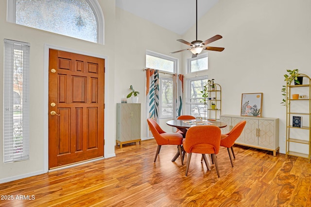 dining space with high vaulted ceiling, light wood-style floors, baseboards, and ceiling fan