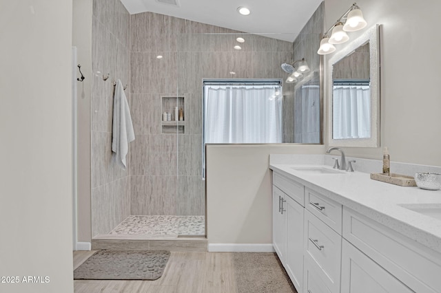 full bathroom featuring a sink, double vanity, tiled shower, visible vents, and wood finished floors