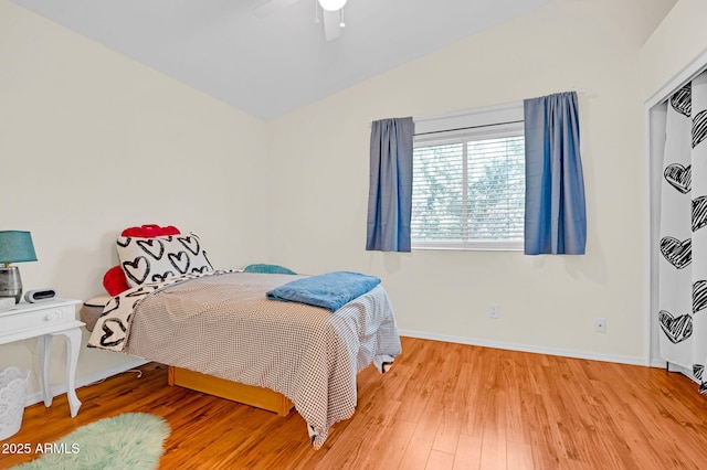 bedroom with ceiling fan, vaulted ceiling, baseboards, and light wood-type flooring