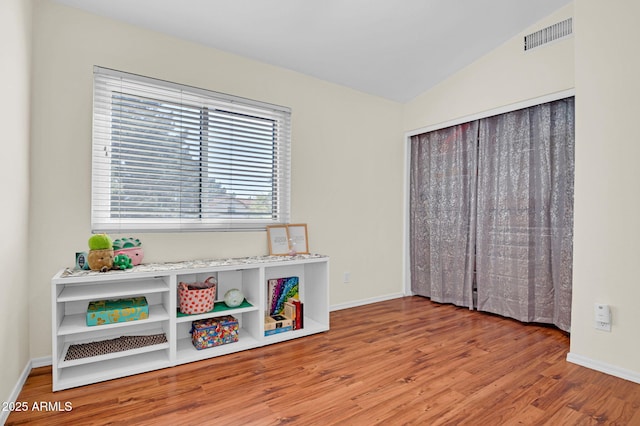 interior space featuring vaulted ceiling, wood finished floors, visible vents, and baseboards