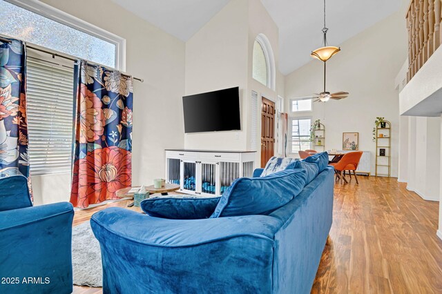 living room featuring wood finished floors, a healthy amount of sunlight, a ceiling fan, and high vaulted ceiling