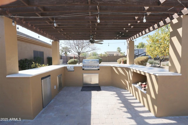 view of patio with an outdoor kitchen, area for grilling, and ceiling fan