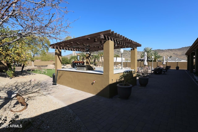 view of patio / terrace with exterior kitchen, a mountain view, and a pergola