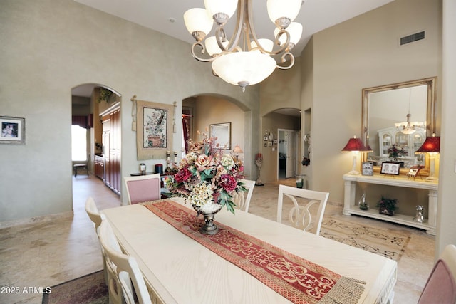 dining area with a towering ceiling and a notable chandelier