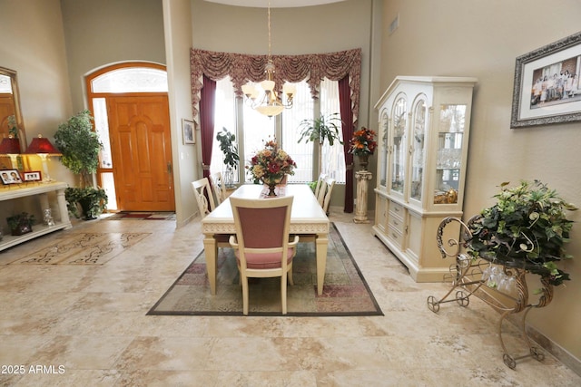 dining space with a towering ceiling and a notable chandelier