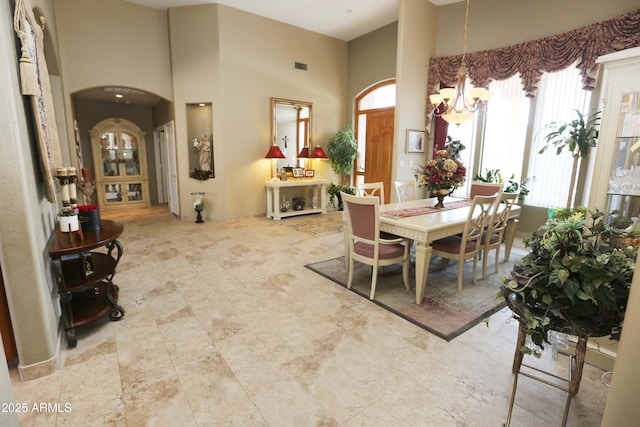 dining space featuring a towering ceiling and a notable chandelier